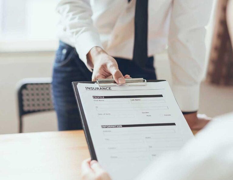 A patient speaking to a healthcare provider while discussing insurance paperwork in a clinic setting.