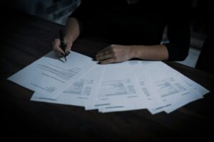 A person reviews a life insurance denial letter beside medical records and financial documents at a kitchen table