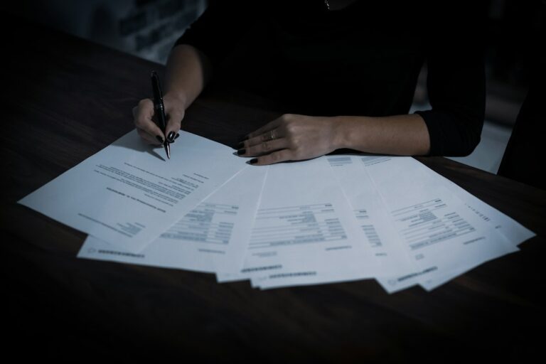 A person reviews a life insurance denial letter beside medical records and financial documents at a kitchen table